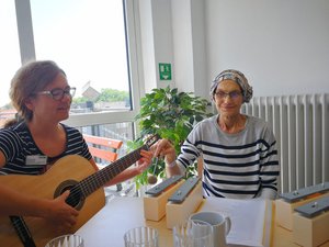 Bild zeigt Mitarbeiterin mit Gitarre und eine Patientin