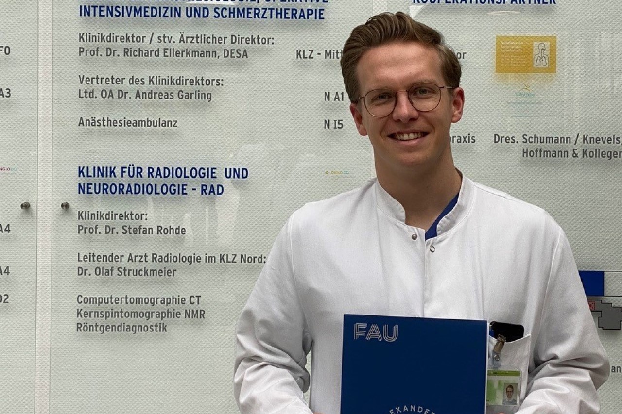 Bild zeigt Sebastian Homann mit Masterarbeit an der Urologischen Klinik