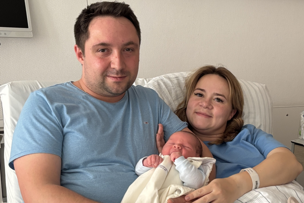 Die glücklichen Eltern mit ihrem Neugeborenen im Arm.